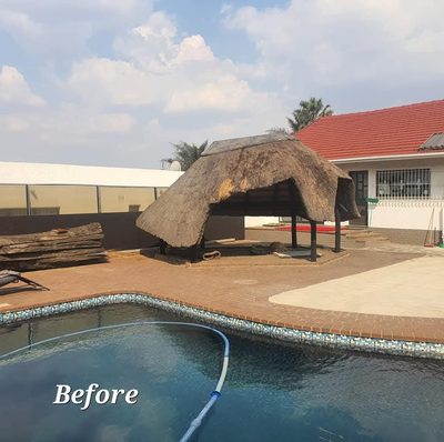 A weathered thatch lapa with a sagging, uneven roof beside a swimming pool, before re-thatching.