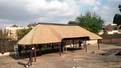 A large open-sided entertainment lapa with an expansive thatch roof carried on timber poles.