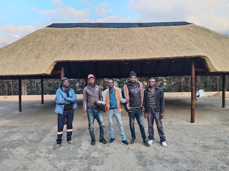 Five members of the Nkosi Thatchers team standing together in front of a newly thatched open lapa.